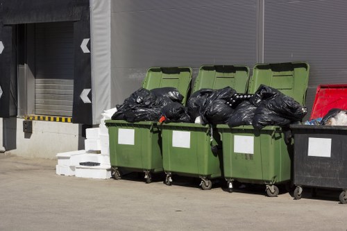 Staff member inspecting a commercial rubbish container and documenting details